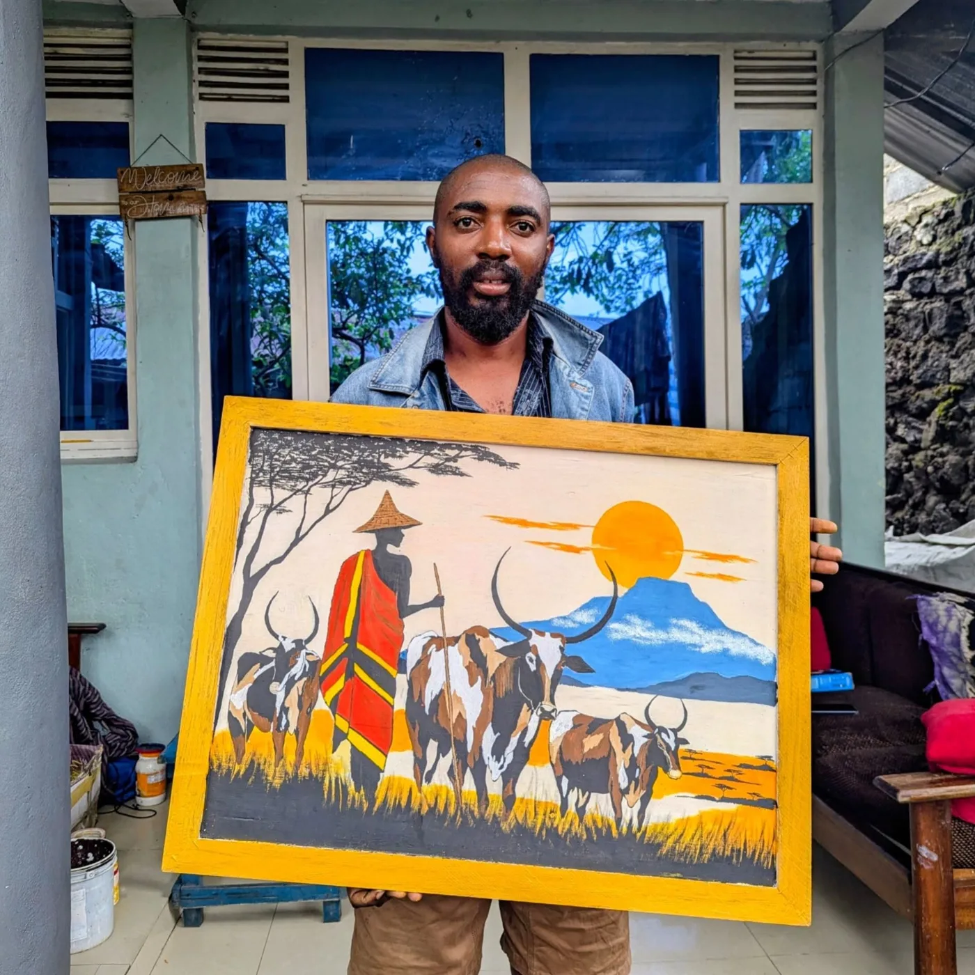 Un artiste du Kivu et l’une de ses œuvres : un berger et son troupeau au pied des montagnes.